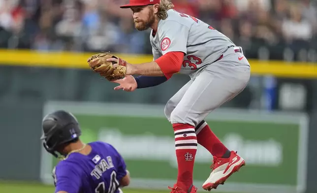 St. Louis Cardinals second baseman Brendan Donovan, right, jumps away from Colorado Rockies' Ezequiel Tovar after forcing him out at second base on a ground ball hit by Brenton Doyle in the first inning of a baseball game Tuesday, Sept. 24, 2024, in Denver. (AP Photo/David Zalubowski)