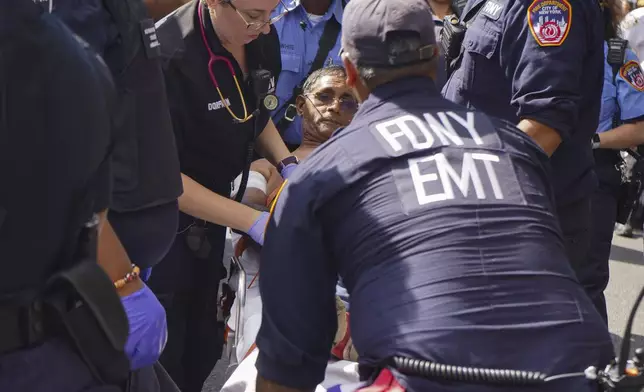 First responders tend to a man injured during a shooting at the West Indian Parade, Monday, Sept. 2, 2024, in the Brooklyn borough of New York. (Nancy Siesel via AP)