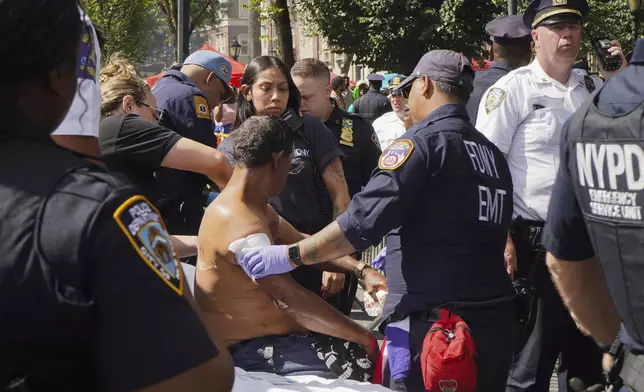 First responders tend to a man injured during a shooting at the West Indian Parade, Monday, Sept. 2, 2024, in the Brooklyn borough of New York. (Nancy Siesel via AP)