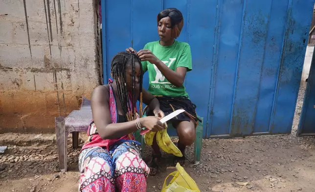 A woman gets her hair braided on the streets of Bangui, Central African Republic, on March 11, 2024. (AP Photo/Sam Mednick)