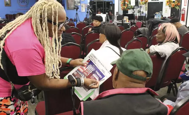 An organizer with the National Action Network signs people in ahead of a Get Out the Vote bus tour toward Philadelphia in the Harlem neighborhood of New York on Friday, Sep. 27, 2024. (AP Photo/Noreen Nasir)