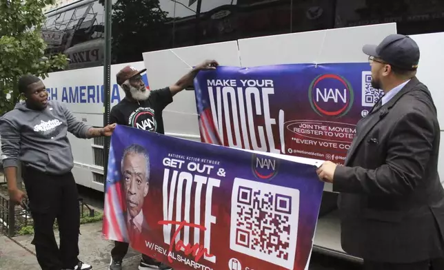 Organizers with the National Action Network put up banners for a Get Out the Vote event as the prepare to depart on a bus tour toward Philadelphia in the Harlem neighborhood of New York on Friday, Sep. 27, 2024. (AP Photo/Noreen Nasir)