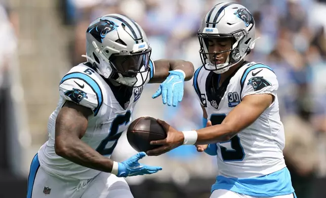 Carolina Panthers quarterback Bryce Young hands off to running back Miles Sanders during the first half of an NFL football game against the Los Angeles Chargers on Sunday, Sept. 15, 2024, in Charlotte, N.C. (AP Photo/Erik Verduzco)