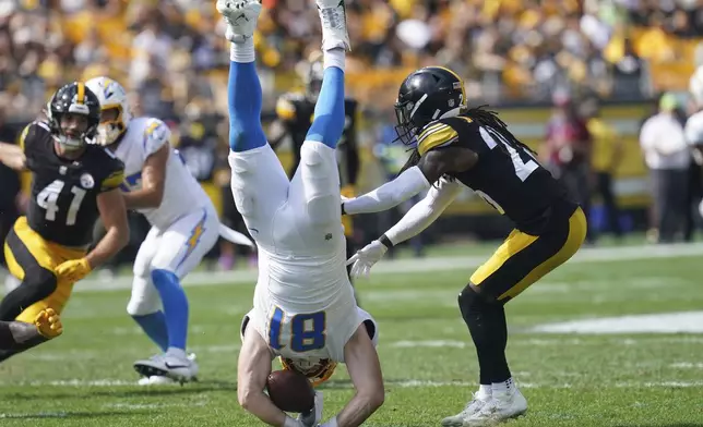 Los Angeles Chargers tight end Will Dissly, center, hits the ground next to Pittsburgh Steelers cornerback Donte Jackson, right, after being tackled by linebacker Patrick Queen during the first half of an NFL football game, Sunday, Sept. 22, 2024, in Pittsburgh. (AP Photo/Matt Freed)