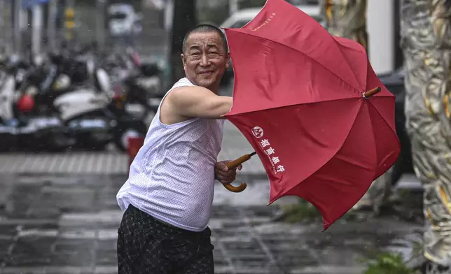 In this photo released by Xinhua News Agency, a man holding an umbrella struggles against the wind following the landfall of typhoon Yagi in Haikou, south China's Hainan Province, Friday, Sept. 6, 2024. (Pu Xiaoxu/Xinhua via AP)