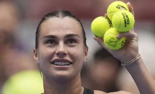 Aryna Sabalenka of Belarus holds up autographed tennis balls to share with fans after her match against Mananchaya Sawangkaew of Thailand during the China Open tennis tournament held at the National Tennis Center in Beijing, Saturday, Sept. 28, 2024. (AP Photo/Ng Han Guan)