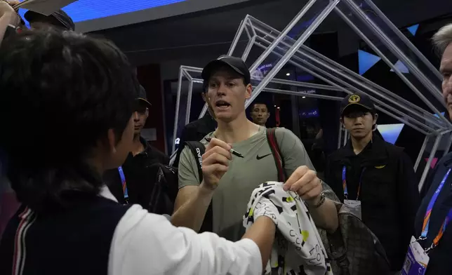 Jannick Sinner of Italy autographs for fans after defeating Roman Safiullin of Russia during the China Open tennis tournament held at the National Tennis Center in Beijing, Saturday, Sept. 28, 2024. (AP Photo/Ng Han Guan)