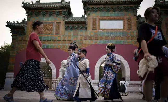 Chinese dressed in Qing Dynasty attire walk at Beihai park in Beijing, China, Sunday, July 28, 2024. (AP Photo/Vincent Thian)