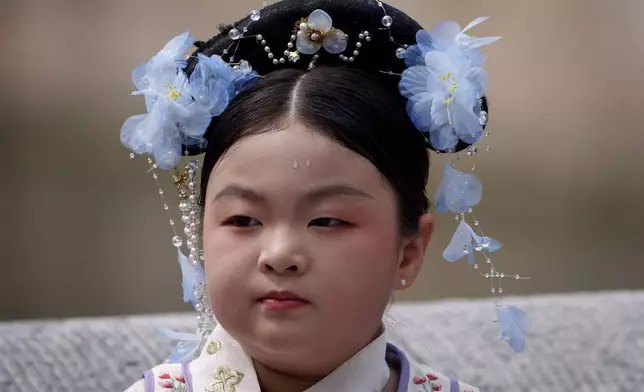 A Chinese girl dressed in Qing Dynasty attire stands for a photograph near the Forbidden city in Beijing, China, Sunday, July 21, 2024. (AP Photo/Vincent Thian)