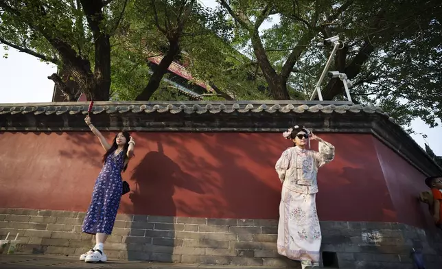 A Chinese girl dressed in Qing Dynasty costume poses for a photograph outside Drum Tower at Gulou East Street in Beijing, China, Wednesday, July 3, 2024. (AP Photo/Vincent Thian)