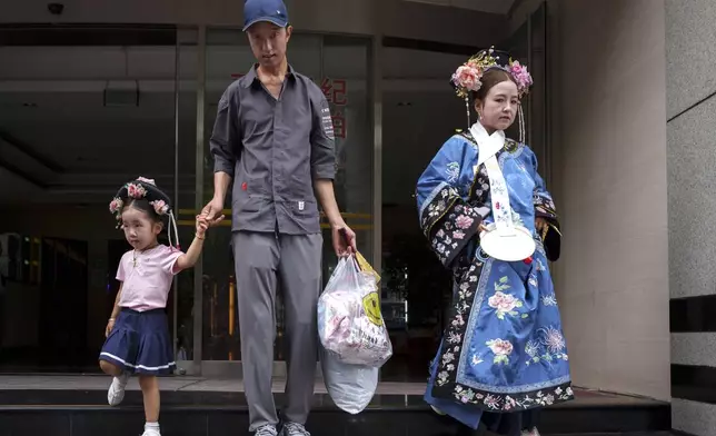 Chinese walk out of a building that provides a one stop solution for achieving the Qing Dynasty traditional look in Beijing, China, Sunday, July 21, 2024. (AP Photo/Vincent Thian)