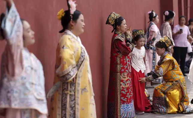 Chinese women dressed in Qing Dynasty attire stands for photographs near the Forbidden city in Beijing, China, Sunday, July 21, 2024. (AP Photo/Vincent Thian)