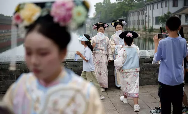 Chinese dressed in Qing Dynasty attire take pictures near the side entrance of Forbidden city in Beijing, China, Monday, July 22, 2024. (AP Photo/Vincent Thian)