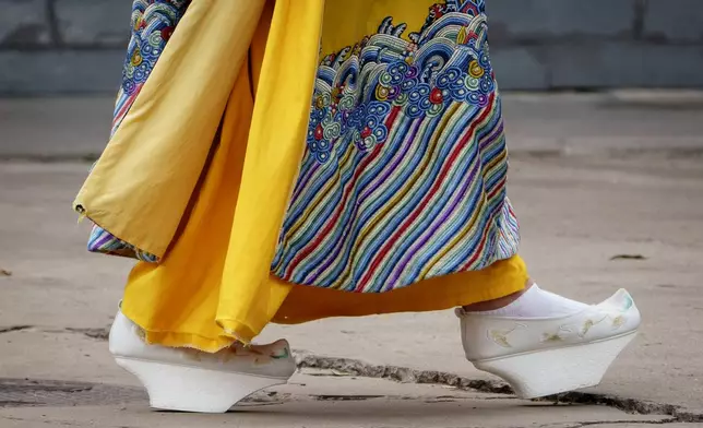 A Chinese woman walks dressed in Qing Dynasty attire with Manchu platform shoes near the Forbidden city in Beijing, China, Sunday, July 21, 2024. (AP Photo/Vincent Thian)