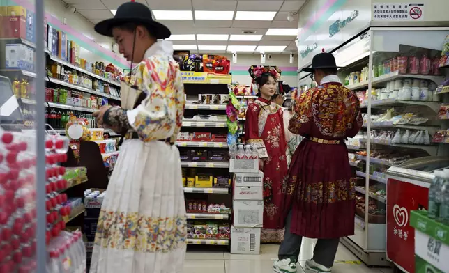 A group of students from the elite Tsinghua University, who celebrated their end of semester dressed in Qing Dynasty attire, shop at a convenience store in Beijing, China, Sunday, July 21, 2024. (AP Photo/Vincent Thian)