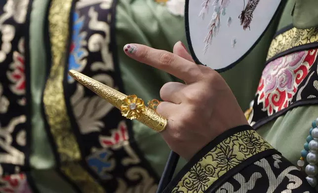 A Chinese woman dressed in Qing Dynasty attire with a fingernail guard takes photographs near the Forbidden city in Beijing, China, Sunday, July 21, 2024. (AP Photo/Vincent Thian)