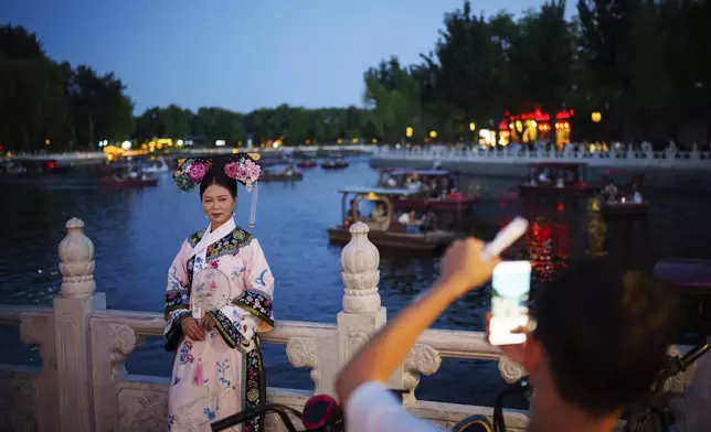 A Chinese girl dressed in Qing Dynasty attire stands for photographs at Shichahai lake in Beijing, China, Tuesday, July 16, 2024. (AP Photo/Vincent Thian)