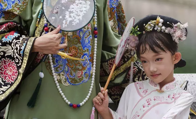 A Chinese girl dressed in Qing Dynasty attire stands for photographs near the Forbidden city in Beijing, China, Sunday, July 21, 2024. (AP Photo/Vincent Thian)