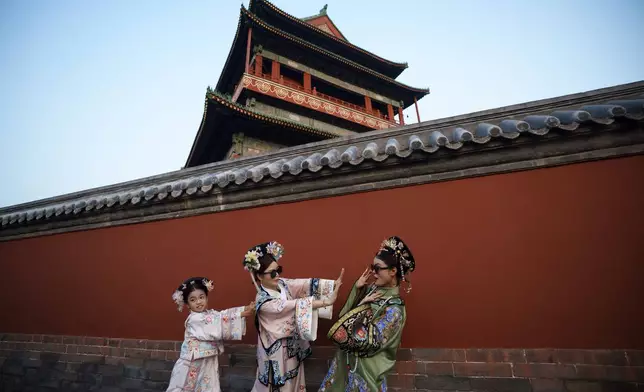 Chinese girls dressed in Qing Dynasty attire take pictures outside the Drum Tower at Gulou East Street in Beijing, China, Tuesday, July 16, 2024. (AP Photo/Vincent Thian)