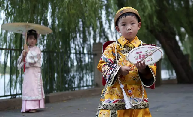 Chinese children dressed in Qing Dynasty royal attire stands for photographs at Beihai park in Beijing, China, Sunday, July 28, 2024. (AP Photo/Vincent Thian)