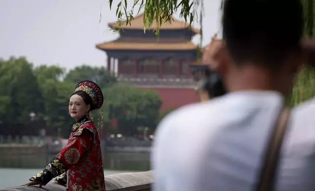 A Chinese woman dressed in Qing Dynasty attire takes pictures near the Forbidden city in Beijing, China, Sunday, July 21, 2024. (AP Photo/Vincent Thian)