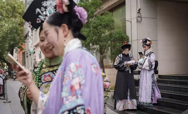 Chinese dressed in Qing Dynasty attire stand at a business building that provides one stop service for the traditional look in Beijing, China, Sunday, July 21, 2024. (AP Photo/Vincent Thian)