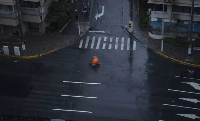 A motorist rides past a quiet road intersection as Typhoon Bebinca made landfall in Shanghai, China, Monday, Sept. 16, 2024. (Chinatopix Via AP)