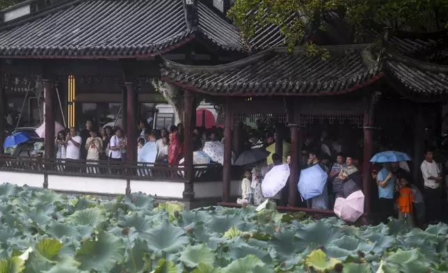 Tourists take shelter in pavilions from the rains brought by Typhoon Bebinca during the Mid-Autumn Festival holiday, in Hangzhou in east China's Zhejiang province, Monday, Sept. 16, 2024. (Chinatopix Via AP)