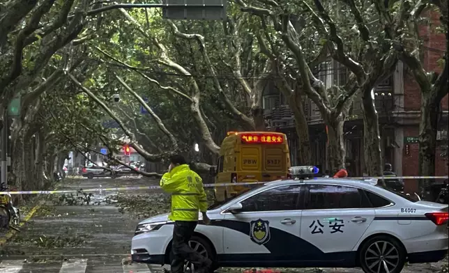 Policemen closed a road as fallen trees along a street in the aftermath of Typhoon Bebinca in Shanghai, China, Monday, Sept. 16, 2024. (Chinatopix Via AP)