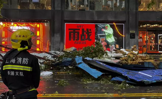 A firefighter stands near debris along a business street in the aftermath of Typhoon Bebinca in Shanghai, China, Monday, Sept. 16, 2024. (Chinatopix Via AP)