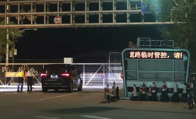 In this photo released by Xinhua News Agency, a policeman directs a motorist as authorities temporary close a road at Lingang new area of the China Pilot Free Trade Zone ahead of the landfall of Typhoon Bebinca in Shanghai, China, Sunday, Sept. 15, 2024. (Fang Zhe/Xinhua via AP)