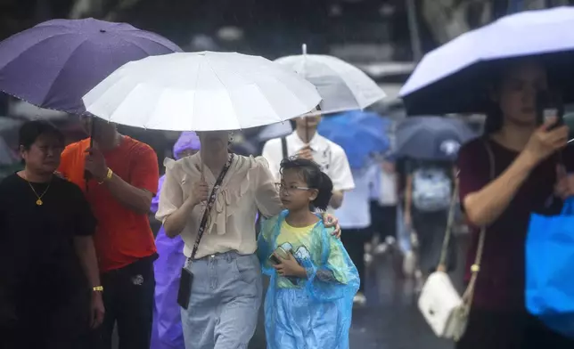 Tourists carrying umbrella tour the West Lake in the rains brought by Typhoon Bebinca during the Mid-Autumn Festival holiday, in Hangzhou in east China's Zhejiang province, Monday, Sept. 16, 2024. (Chinatopix Via AP)