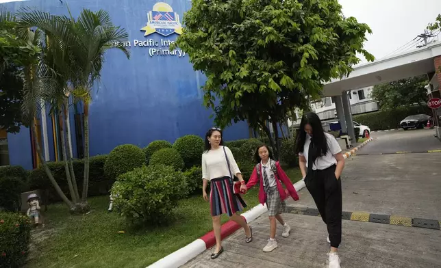 Chinese mother Du Xuan, left, picks up her daughters May Yu, center, and Annie Yu from school in Chiang Mai province, Thailand, Tuesday, April 23, 2024. (AP Photo/Sakchai Lalit)