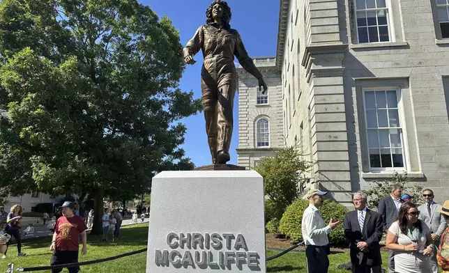 Sculptor Benjamin Victor (in baseball cap) speaks to Steven McAuliffe, former husband of teacher Christa McAuliffe who died when the space shuttle Challenger broke apart in 1986, as they stand next to a statue unveiled on what would've been Christa McAuliffe's 76th birthday, Monday, Sept. 2, 2024, in Concord, N.H. (AP Photo/Nick Perry)