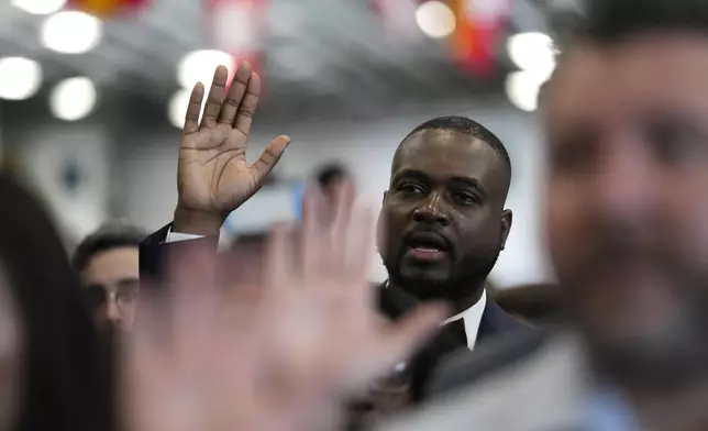 FILE - Smith Fisnord of Haiti raises his right hand as the takes the Oath of Allegiance to the United States of America during a naturalization ceremony aboard the USS Bataan during Fleet Week Miami at PortMiami, Tuesday, May 7, 2024, in Miami. (AP Photo/Lynne Sladky, File)