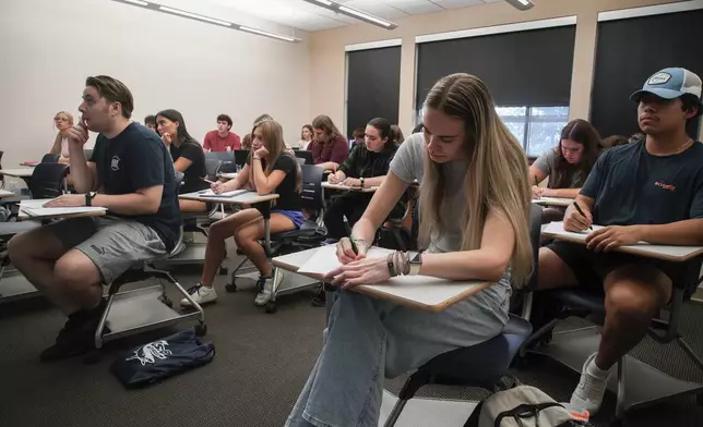 Audra Hillman, 18, foreground right, a freshman at the University of South Carolina Beaufort, takes a modified citizenship quiz during an American government class in Bluffton, S.C., on Tuesday, Aug. 20, 2024. (AP Photo/Allen G. Breed)