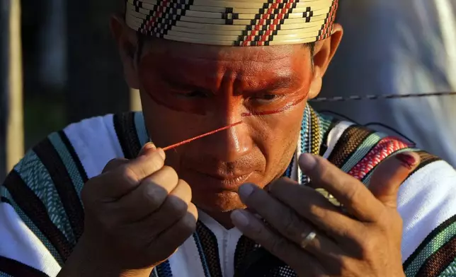 An Ashaninka Indigenous man applies face paint during the annual celebration recognizing the Ashaninka territory in the Apiwtxa village, Acre state, Brazil, Monday, June 24, 2024. (AP Photo/Jorge Saenz)