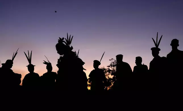 Ashaninka Indigenous people from Brazil and Peru dance and sing at dawn during the annual celebration recognizing the Ashaninka territory in the Apiwtxa village, Acre state, Brazil, Monday, June 24, 2024. (AP Photo/Jorge Saenz)