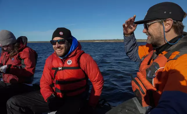 Flavio Lehner, center, chief climate scientist at Polar Bears International, rides in a boat while looking along the Hudson Bay shores for polar bears, Monday, Aug. 5, 2024, near Churchill, Manitoba. (AP Photo/Joshua A. Bickel)