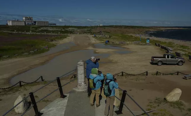 Tourists take photos of Hudson Bay while standing on an old whaling boat, Saturday, Aug. 3, 2024, in Churchill, Manitoba. (AP Photo/Joshua A. Bickel)