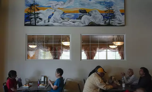 Patrons eat lunch below a mural depicting polar bears and other wildlife, Monday, Aug. 5, 2024, at the Seaport Hotel in Churchill, Manitoba. (AP Photo/Joshua A. Bickel)