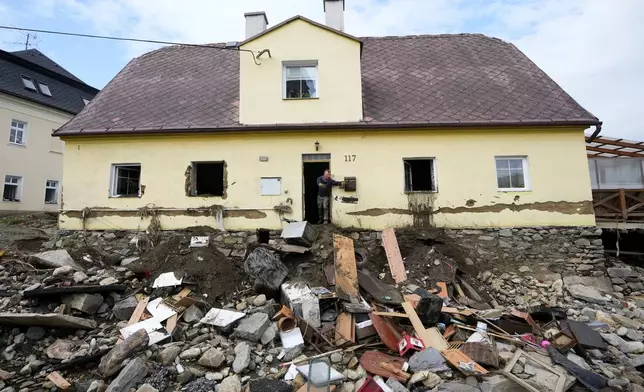 FILE - A man throws damaged goods and furniture off a house as residents return to clean up after recent floods in Mikulovice, Czech Republic, Sept. 19, 2024. (AP Photo/Petr David Josek, File)