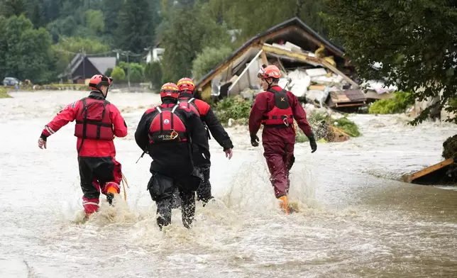 FILE - Firefighters walk through a flooded road of Jesenik, Czech Republic, Sept. 15, 2024. (AP Photo/Petr David Josek, File)