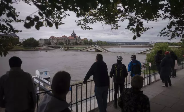 FILE - Spectators look at the partially collapsed Carolabrucke bridge, over the Elbe, which is rising rapidly due floodwaters, in front of the state chancellery in Dresden, Germany, Sept. 15, 2024. (AP Photo/Markus Schreiber)