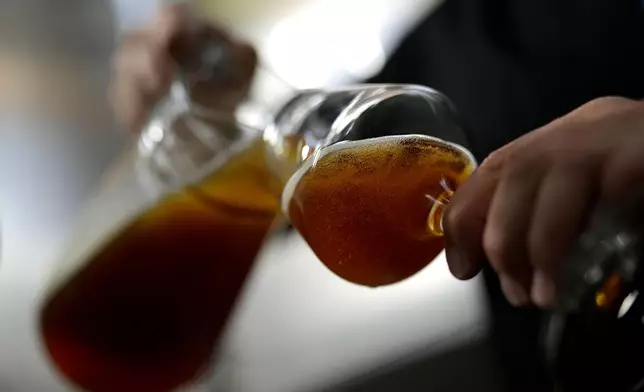 An employee of the Technical University of Munich fills beer in the brewery in Freising, Germany, Thursday, Sept. 19, 2024. (AP Photo/Matthias Schrader)