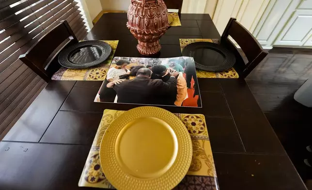 A photo sits on the dining table in the Laster family home, showing Phillip Laster Jr. coming up to the altar and bowing his head to accept Christ, a few months before his passing, at St. Paul Church of God in Christ, in Brandon, Miss., Tuesday, Aug. 27, 2024. (AP Photo/Gerald Herbert)