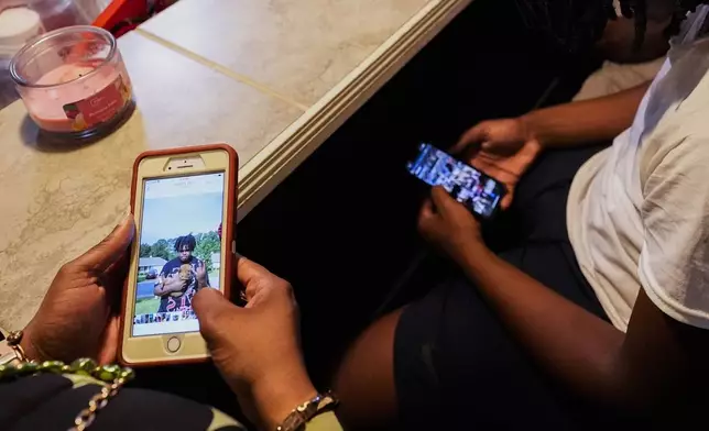 Ashanta Laster, left, shares photos of her son Phillip Laster Jr., with his friend Antwan Agee, at the Laster home in Brandon, Miss., Tuesday, Aug. 27, 2024. (AP Photo/Gerald Herbert)