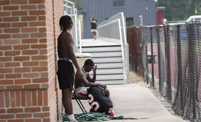 Members of the Baker High football team wait out a weather delay at practice in Baker, La., Wednesday, Aug. 28, 2024. (AP Photo/Gerald Herbert)