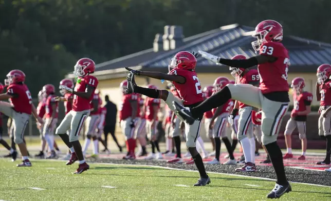 Members of the Brandon High freshman football team warm up before a game against Clinton High in Brandon, Miss., Tuesday, Aug. 27, 2024. (AP Photo/Gerald Herbert)