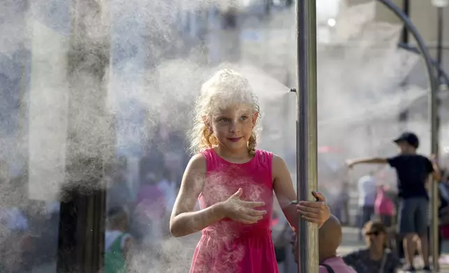 FILE - Anna, 7, cools off under a misting fountain on a hot afternoon during the 2024 Summer Olympics, Monday, July 29, 2024, in Paris, France. (AP Photo/Vadim Ghirda, File)